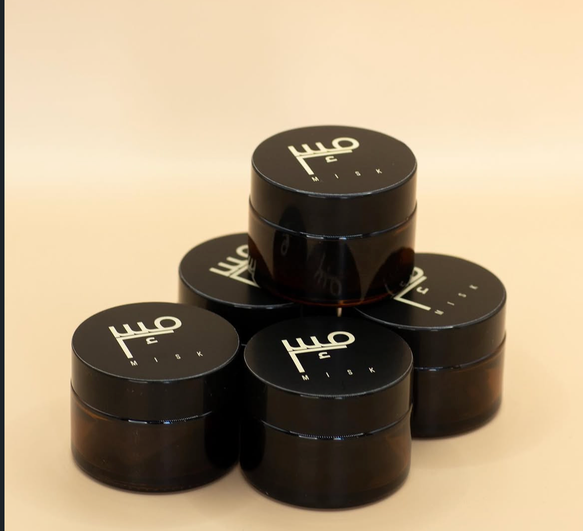 Stacked jars of Misk bakhoor, each lid carrying the Misk calligraphy mark