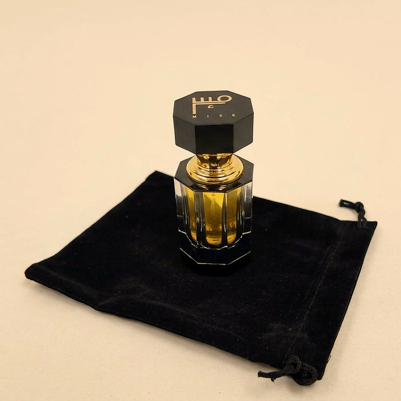 A Misk perfume oil bottle on its black velvet pouch